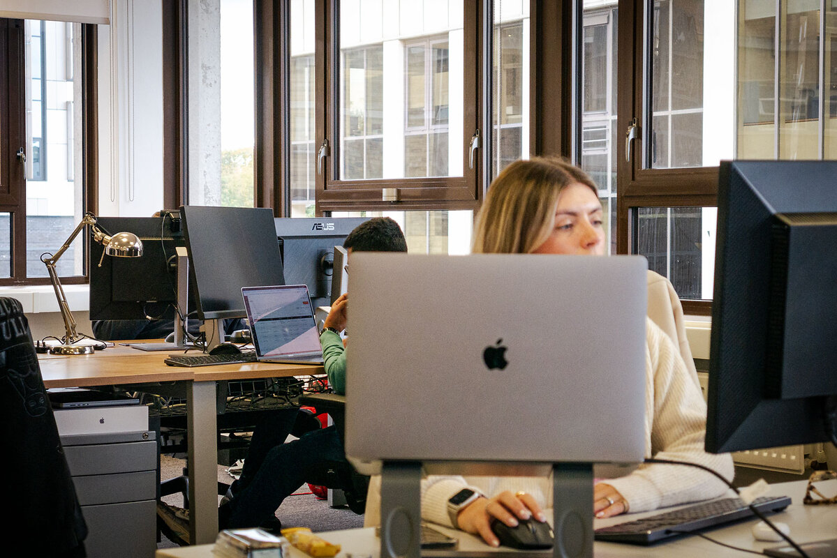 Laptop with office workers in background