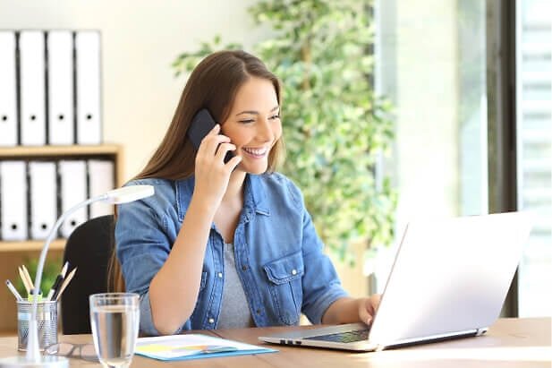 Happy smiling woman using phone at desk