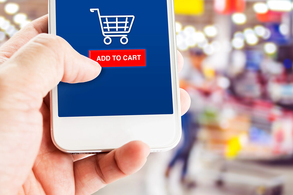 Hand holding mobile phone with blur customer at supermarket store background,Shopping online concept,E-commerce business