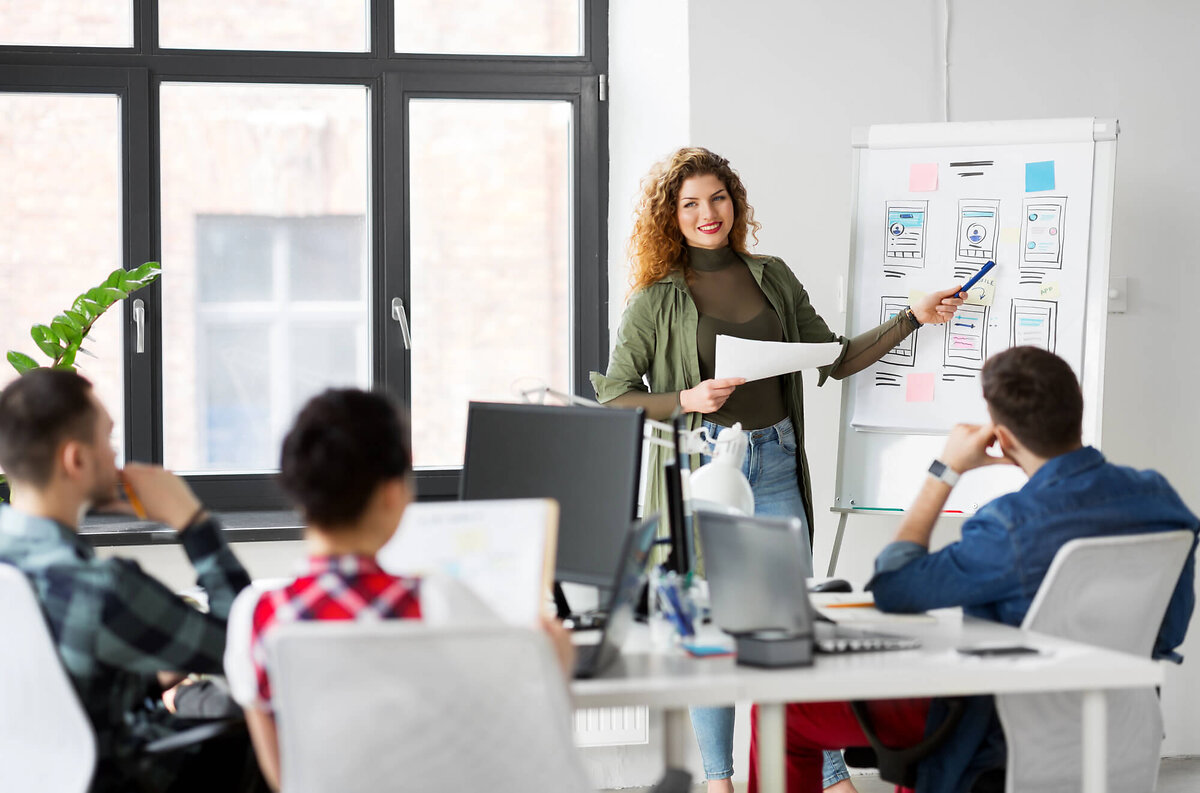 Woman pointing at flipchart, men listening