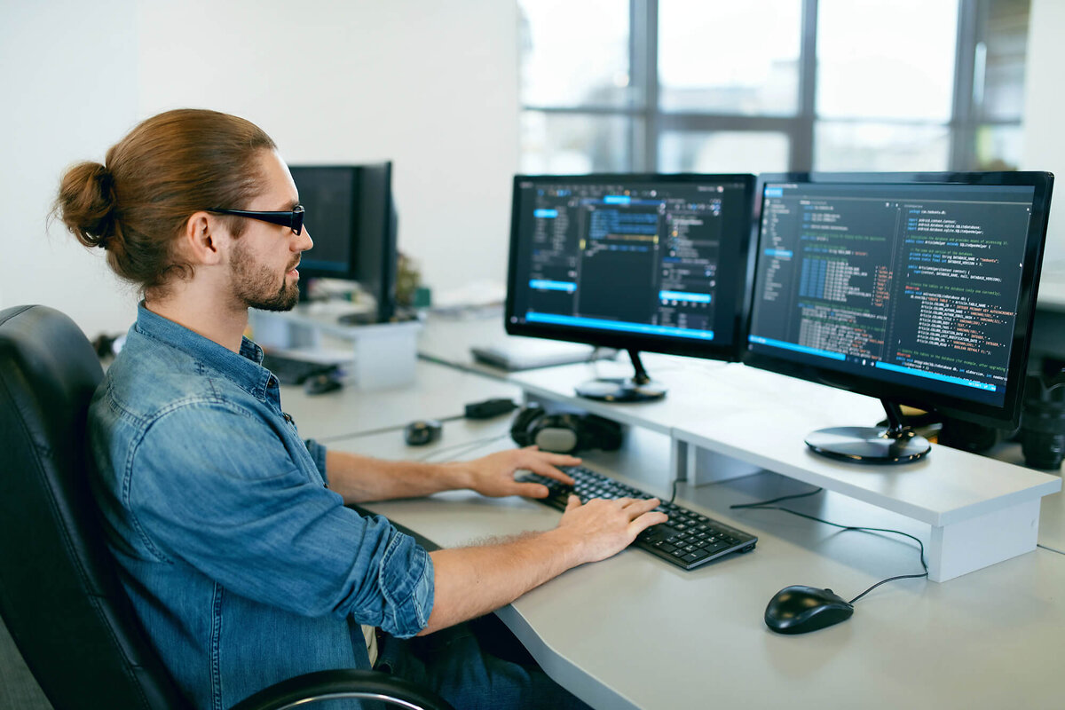 Man coding on two monitors
