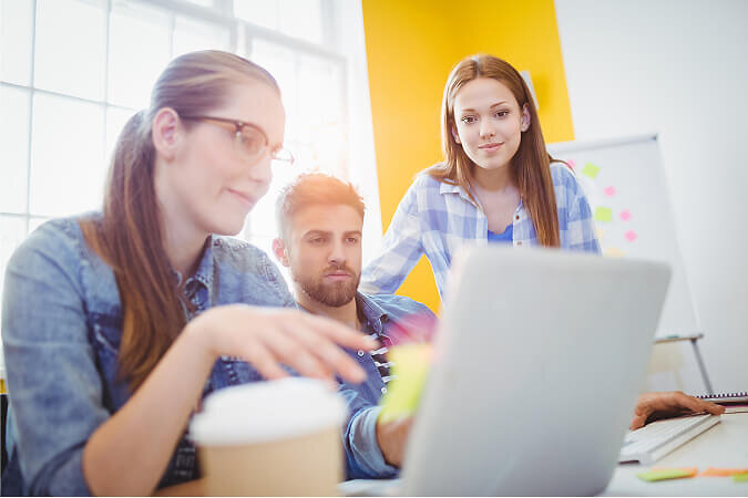Group of three staff looking at laptop