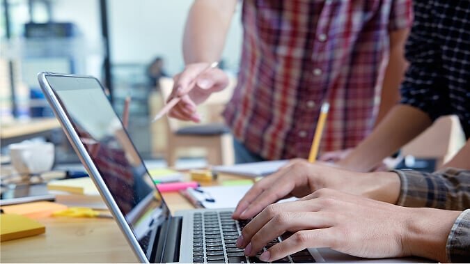 Man pointing at laptop with pencil