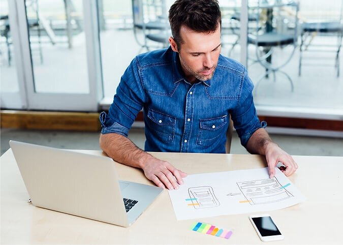 Man at desk examining image on paper