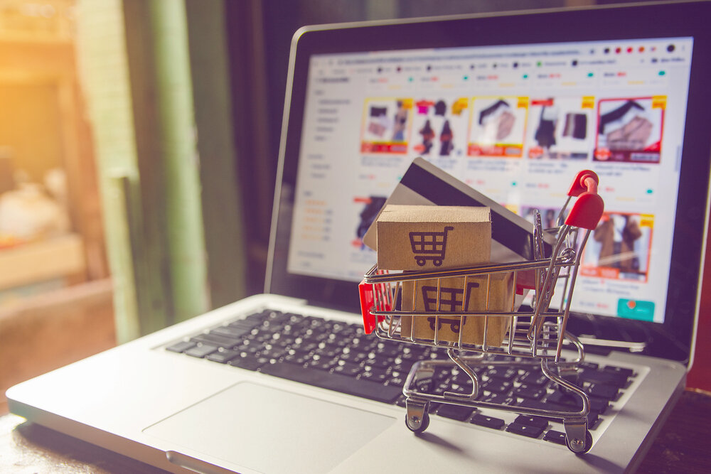 Shopping online concept - Parcel or Paper cartons with a shopping cart logo in a trolley on a laptop keyboard. Shopping service on The online web. with payment by credit card and offers home delivery.