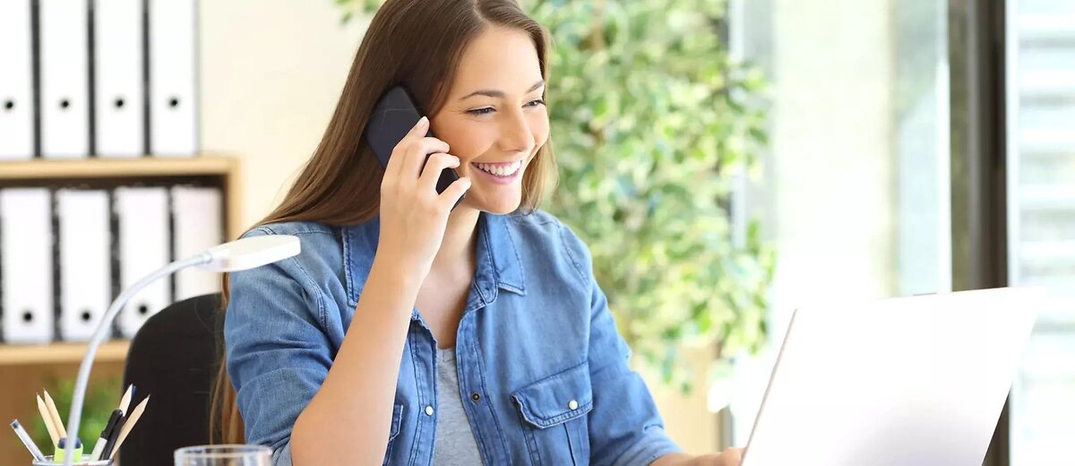 Happy Smiling Woman Using Phone At Desk