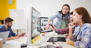 Workers Around A Computer Screen, Pointing With Stylus
