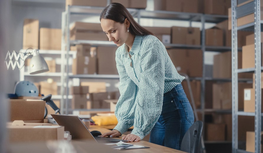 Woman At Laptop Surrounded By Packaging